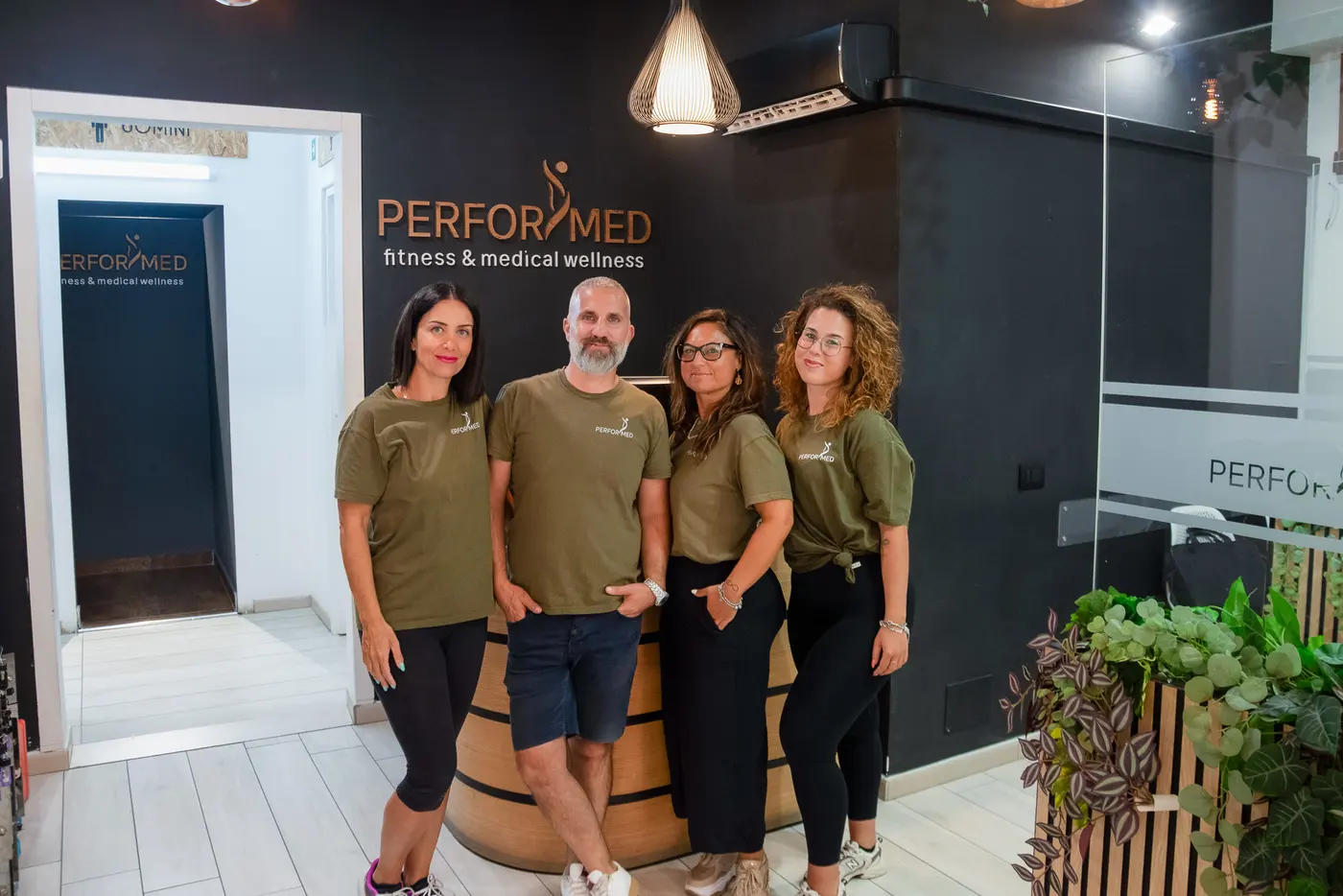 Lo staff della reception in posa davanti al logo PERFORMED